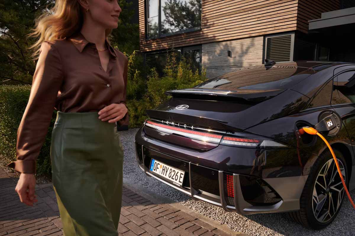 Hyundai IONIQ 6 von hinten während er lädt. Eine Frau geht vorbei